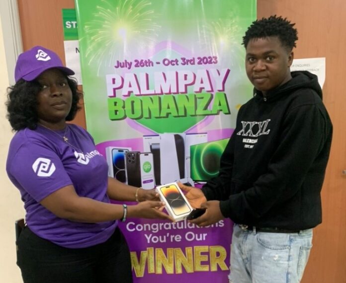 A PalmPay Agent presenting an iPhone 14 Pro Max to Ovedje Destiny from Delta State for winning this week's raffle draw
